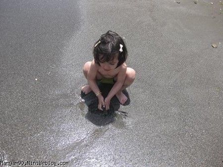 دختری کنار ساحل در حال ماسه بازی